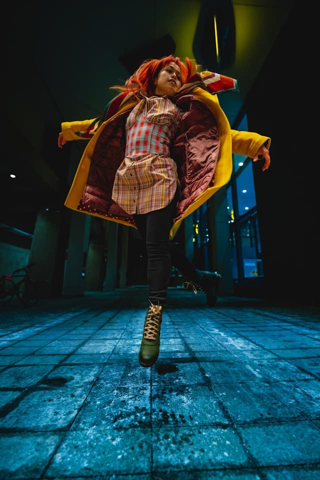 A woman in a red and yellow coat is dancing